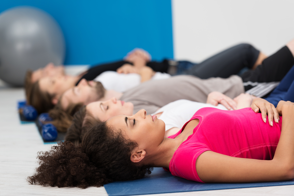 group of people relaxing on mats in a stress relief class