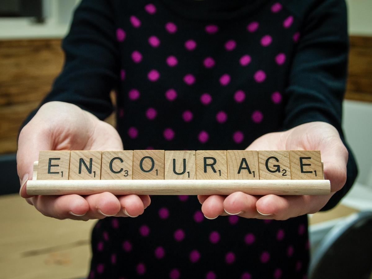 Scrabble letters forming 'encourage' words.